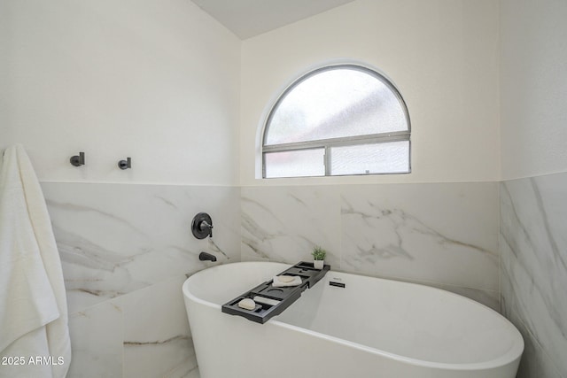 bathroom with tile walls and a tub to relax in