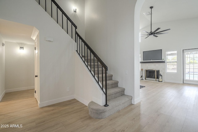 stairway featuring hardwood / wood-style floors, ceiling fan, and a high ceiling