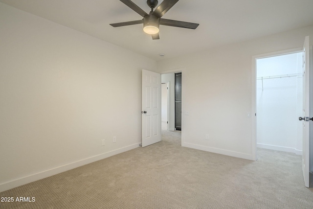 unfurnished bedroom with ceiling fan, light colored carpet, a closet, and a walk in closet