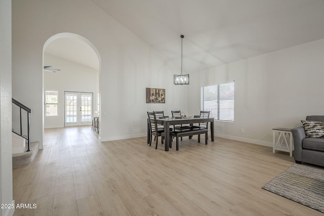 dining room featuring high vaulted ceiling, light hardwood / wood-style floors, french doors, and a chandelier