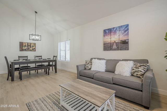 living room with vaulted ceiling, a chandelier, and light hardwood / wood-style flooring