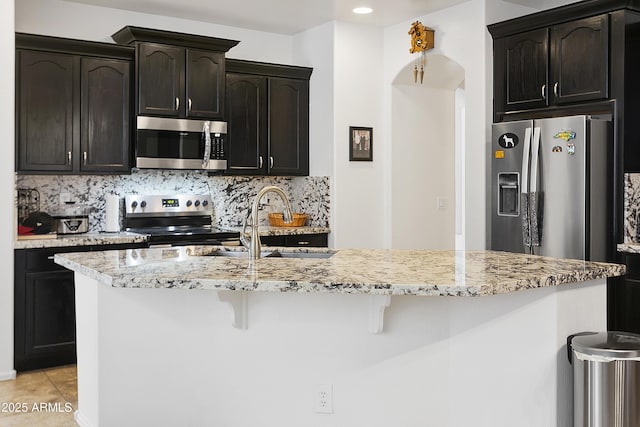 11959 W Vernon Ave, Avondale, AZ 85392 - kitchen with a kitchen bar, backsplash, a sink, light stone counters, and appliances with stainless steel finishes