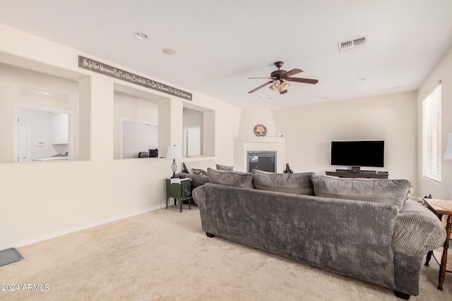 living room with ceiling fan, a fireplace, and light colored carpet