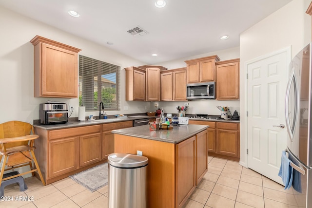 kitchen featuring light tile patterned flooring, sink, a kitchen island, and stainless steel appliances