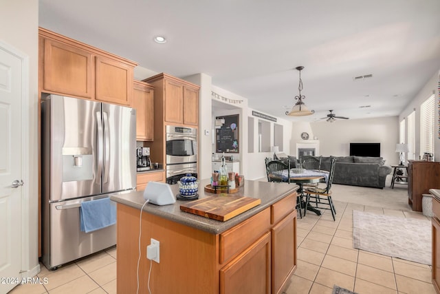 kitchen featuring a center island, ceiling fan, light tile patterned floors, decorative light fixtures, and stainless steel appliances