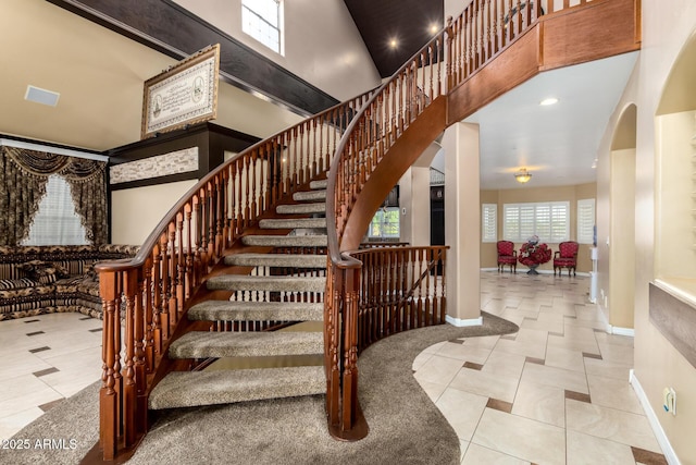 stairs featuring a towering ceiling and tile patterned floors