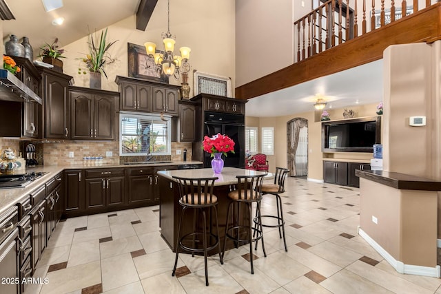 kitchen featuring backsplash, refrigerator, a chandelier, stainless steel gas stovetop, and dark brown cabinets