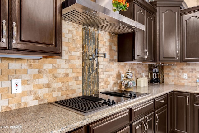 kitchen featuring dark brown cabinetry, stainless steel gas stovetop, wall chimney exhaust hood, and backsplash