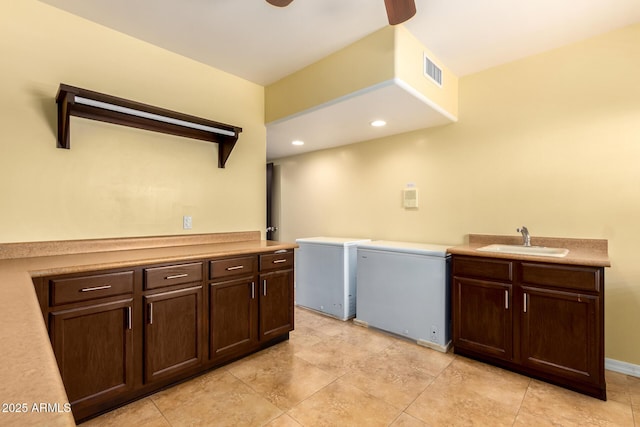 laundry area featuring washer and dryer, ceiling fan, cabinets, and sink