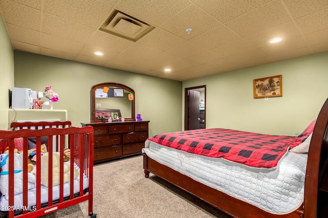 carpeted bedroom featuring a drop ceiling