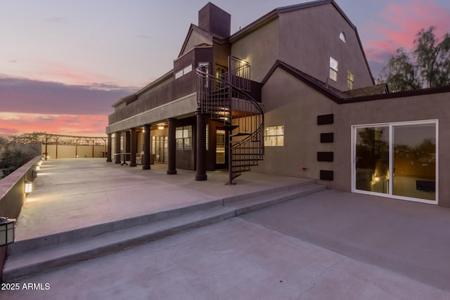 back house at dusk featuring a patio