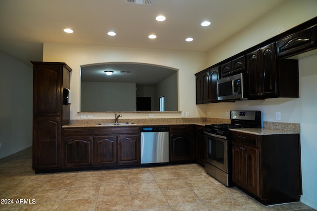 kitchen featuring stainless steel appliances, dark brown cabinetry, sink, and light tile patterned floors