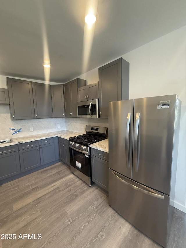 3824 W Puget Ave, Phoenix, AZ 85051 - kitchen featuring stainless steel appliances, light wood-style flooring, tasteful backsplash, light stone countertops, and gray cabinets
