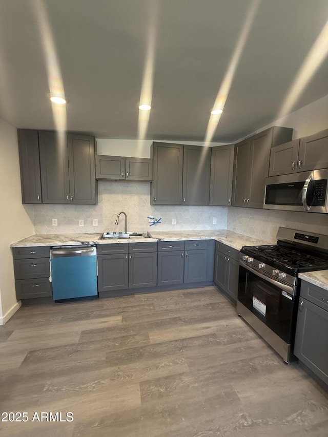 3824 W Puget Ave, Phoenix, AZ 85051 - kitchen with stainless steel appliances, decorative backsplash, gray cabinets, and light wood-style flooring