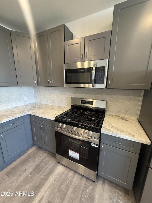 3824 W Puget Ave, Phoenix, AZ 85051 - kitchen with appliances with stainless steel finishes, light wood-style flooring, gray cabinetry, and tasteful backsplash