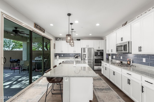 kitchen featuring white cabinetry, an island with sink, pendant lighting, and appliances with stainless steel finishes