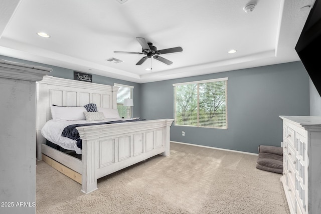 carpeted bedroom with ceiling fan and a raised ceiling