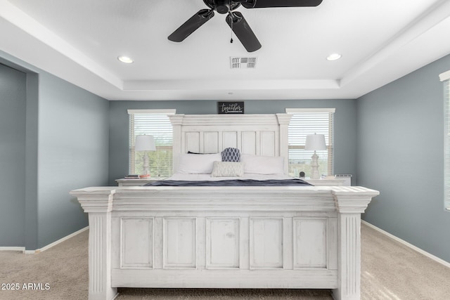 bedroom with multiple windows, ceiling fan, and light carpet