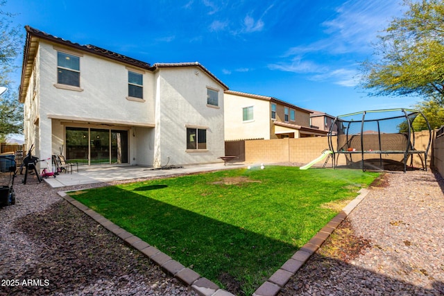 rear view of property with a playground, a patio, a trampoline, and a lawn