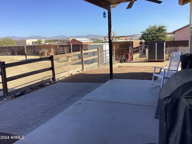 view of patio with a mountain view, an outbuilding, and ceiling fan