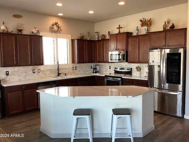 kitchen featuring a breakfast bar, a center island, sink, dark hardwood / wood-style floors, and appliances with stainless steel finishes