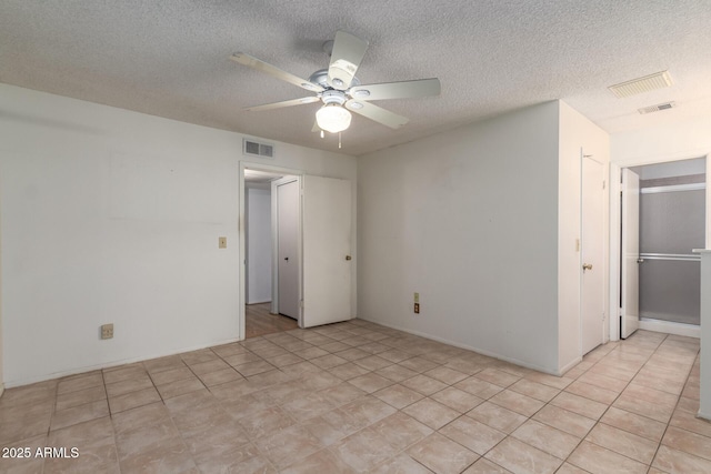 empty room with visible vents, a textured ceiling, and ceiling fan