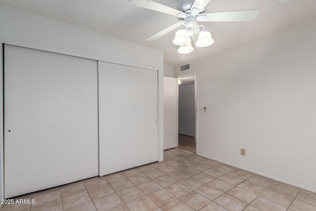 unfurnished bedroom featuring a closet, visible vents, ceiling fan, and light tile patterned flooring