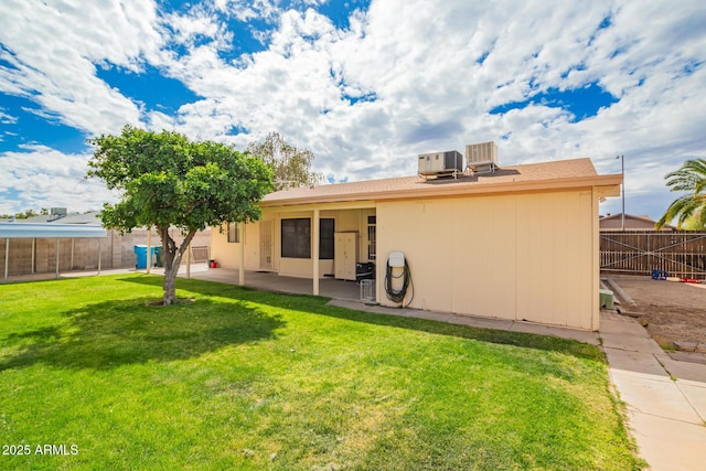 back of property with a yard, central air condition unit, fence private yard, and a patio area