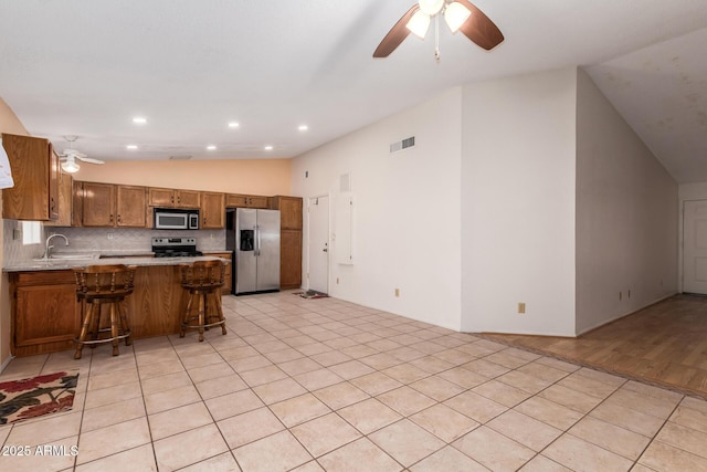 kitchen featuring visible vents, brown cabinets, a sink, appliances with stainless steel finishes, and lofted ceiling