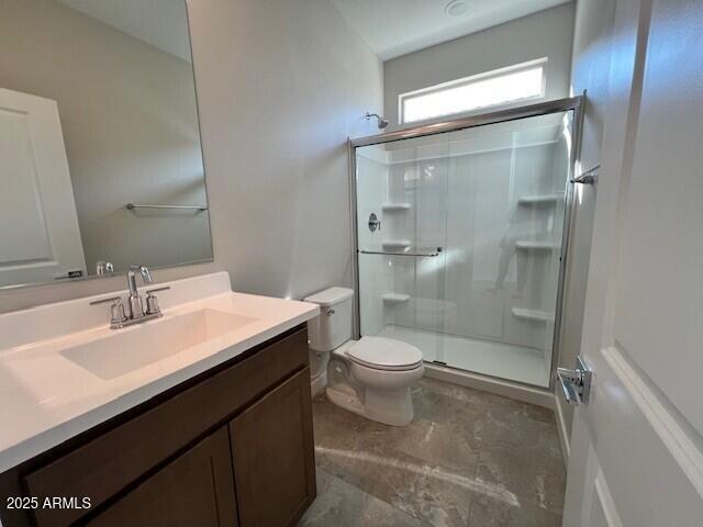 bathroom featuring vanity, a shower with door, and toilet