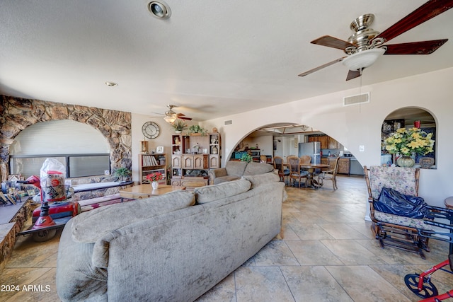 tiled living room with a textured ceiling and ceiling fan