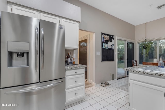 kitchen featuring white cabinets, stainless steel fridge, a chandelier, and light stone counters