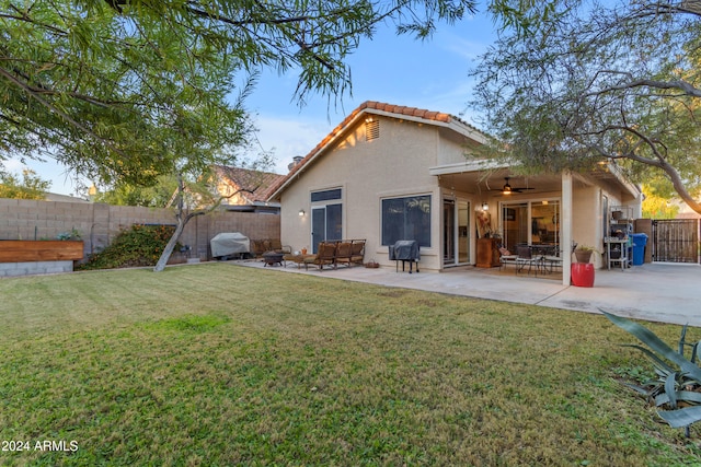 rear view of property featuring ceiling fan, a patio area, and a lawn