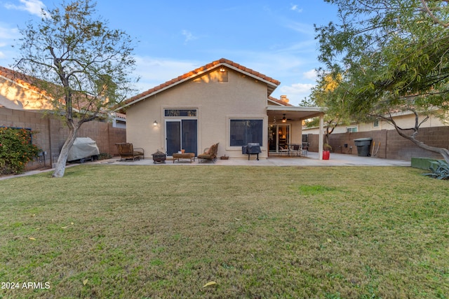 rear view of property featuring a lawn, ceiling fan, and a patio