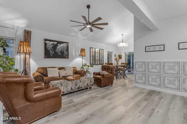 living room with ceiling fan with notable chandelier, lofted ceiling, and light hardwood / wood-style flooring