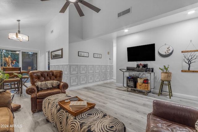 living room with light wood-type flooring, high vaulted ceiling, and ceiling fan