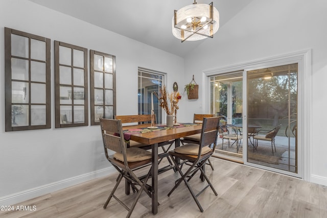 dining room with an inviting chandelier, vaulted ceiling, and light wood-type flooring