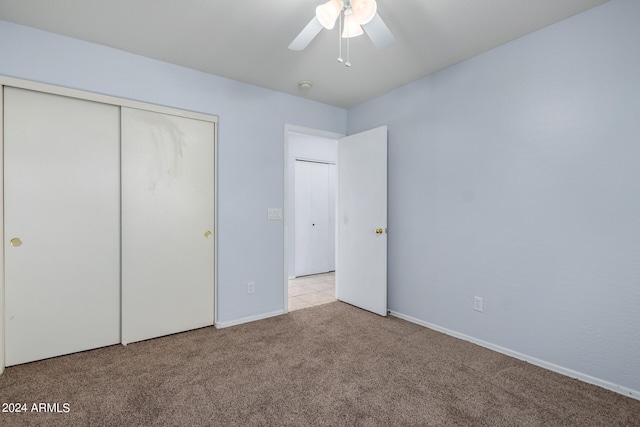 unfurnished bedroom with ceiling fan, light carpet, and a closet