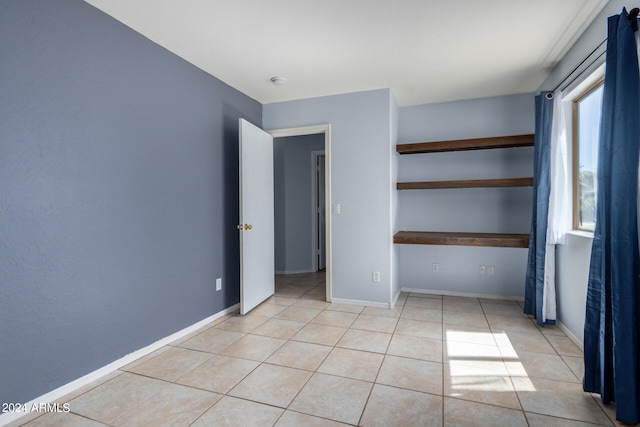 unfurnished bedroom with light tile patterned flooring, a closet, and multiple windows