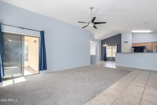 unfurnished living room with light carpet, ceiling fan with notable chandelier, a healthy amount of sunlight, and vaulted ceiling