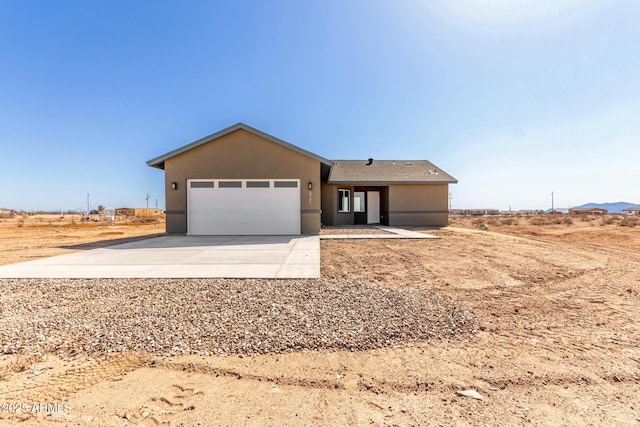 ranch-style house featuring stucco siding, a garage, and driveway