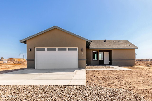 single story home with concrete driveway, an attached garage, roof with shingles, and stucco siding