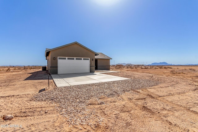 garage with a mountain view, central air condition unit, and concrete driveway