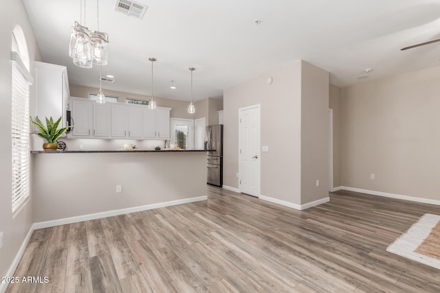 kitchen featuring dark countertops, stainless steel fridge, light wood-type flooring, a peninsula, and recessed lighting
