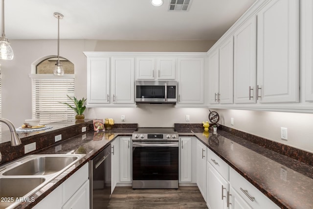 kitchen with appliances with stainless steel finishes, a sink, white cabinets, and dark wood-type flooring