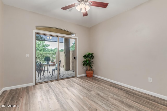 empty room featuring wood finished floors, baseboards, and ceiling fan