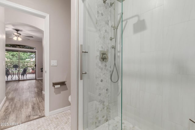 bathroom with a stall shower, ceiling fan, baseboards, and toilet