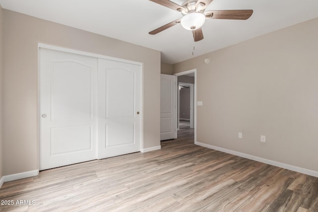 unfurnished bedroom featuring baseboards, light wood-style floors, a closet, and ceiling fan