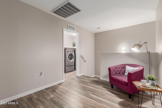living area with washer / clothes dryer, wood finished floors, and baseboards