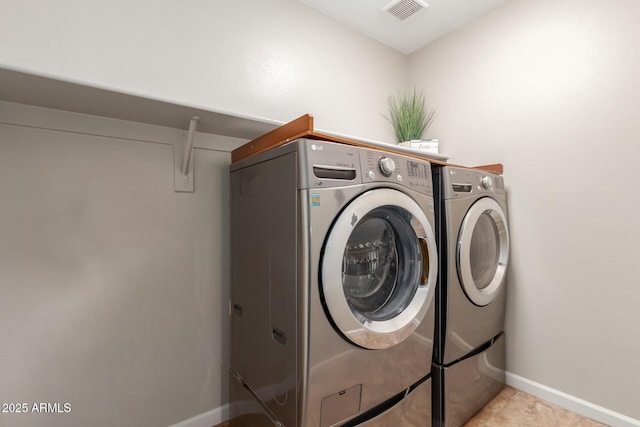 washroom featuring washer and clothes dryer, baseboards, and light tile patterned floors